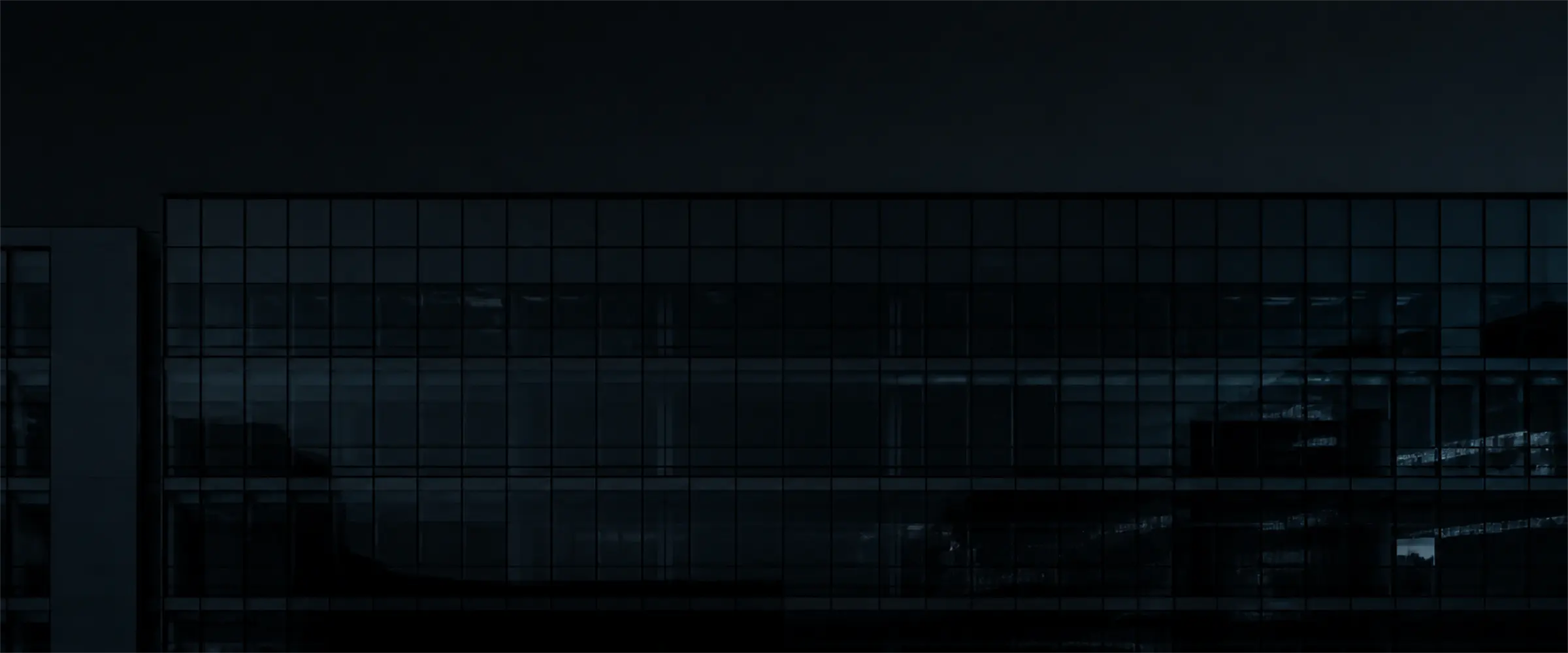A dark glass facade at night.